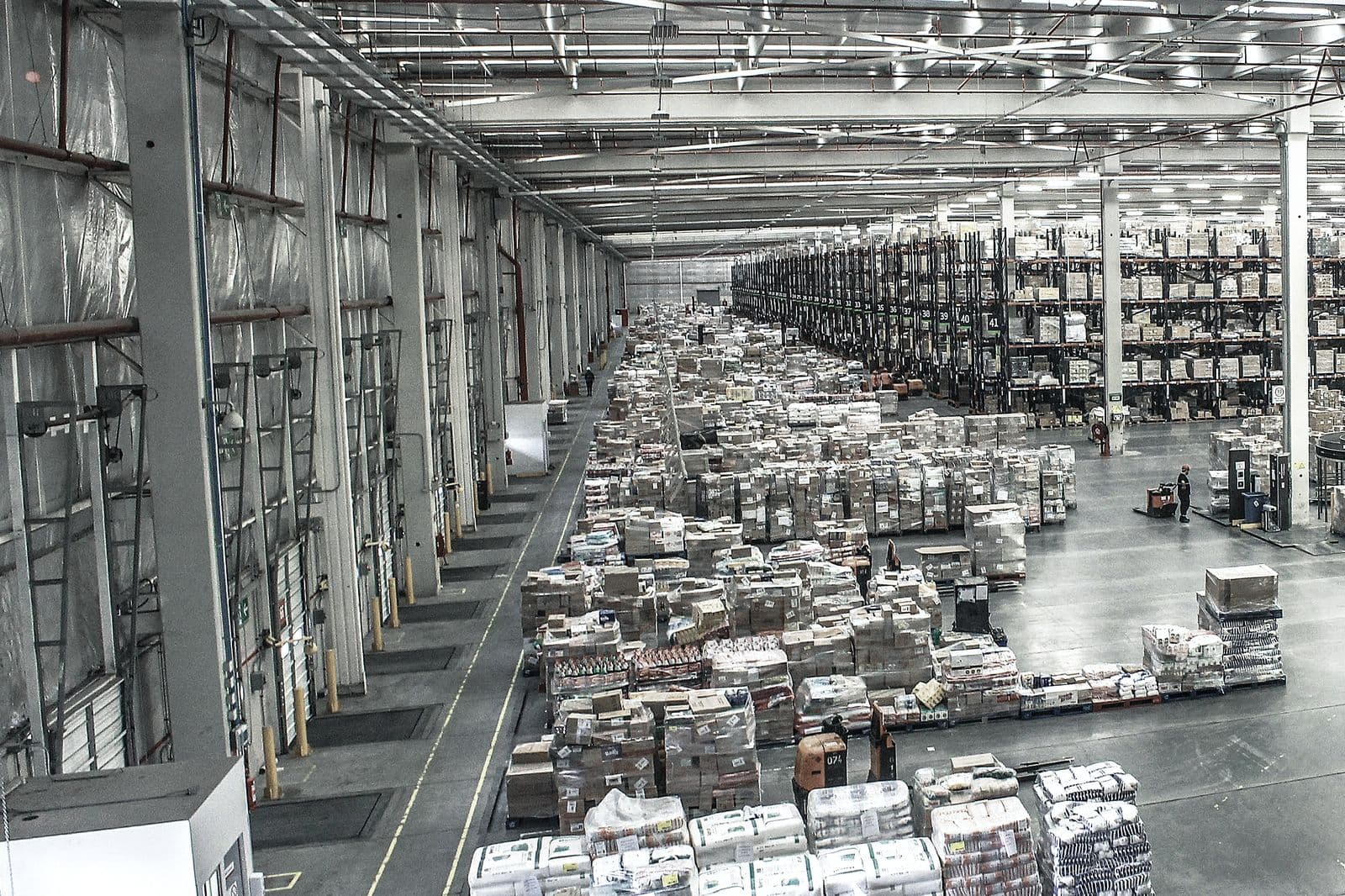 Nave de distribución con palés filmados y etiquetados alineados junto a los muelles de expedición