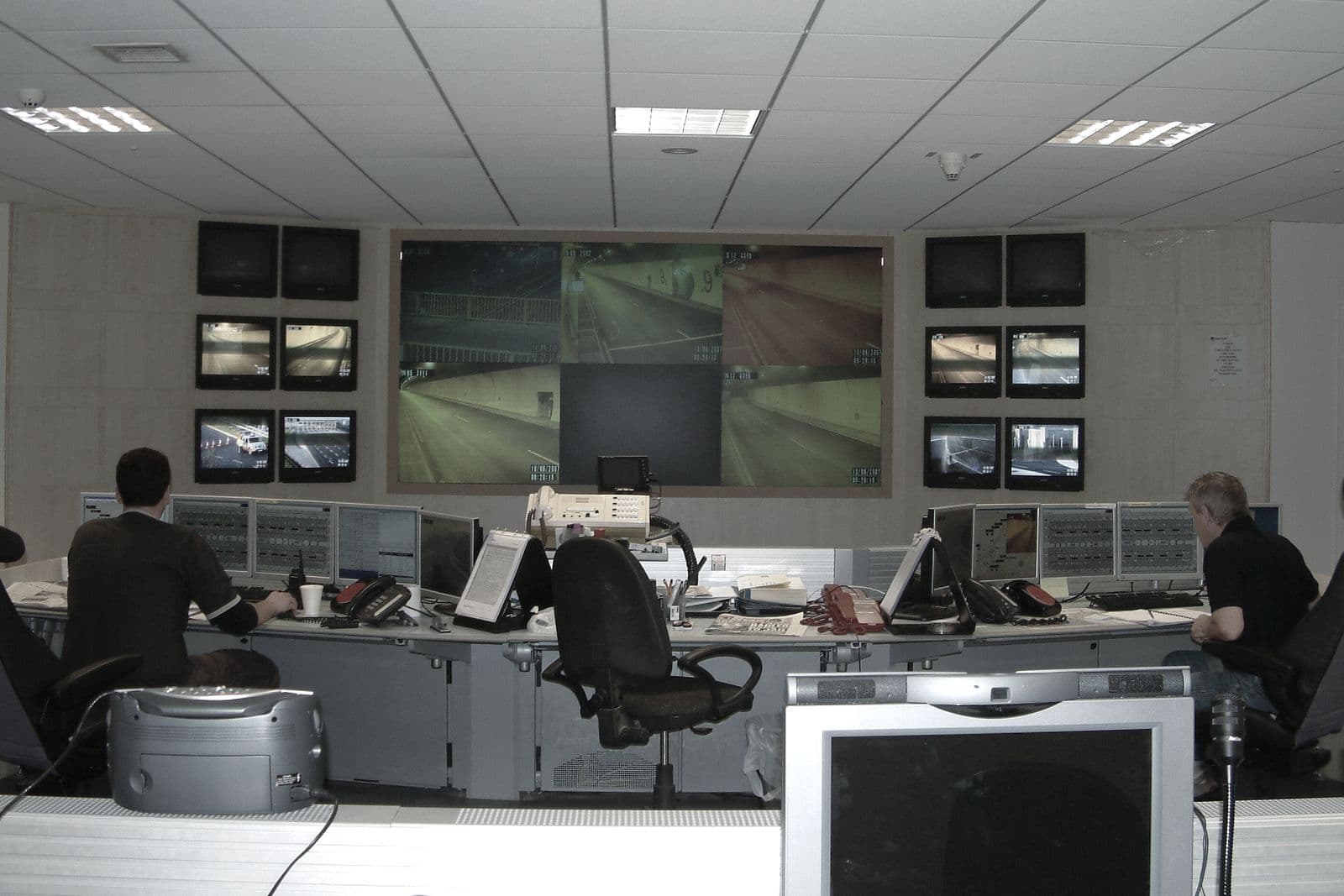 Sala de control de tráfico con videowall de cámaras y operadores de espaldas ante pantallas